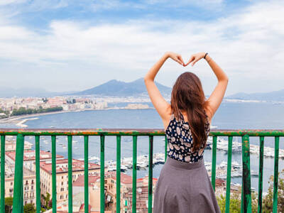 Beautiful Girl Making Heart Shape with arms, Naples City with mount Vesuvius are in background, concept: love Naples.
